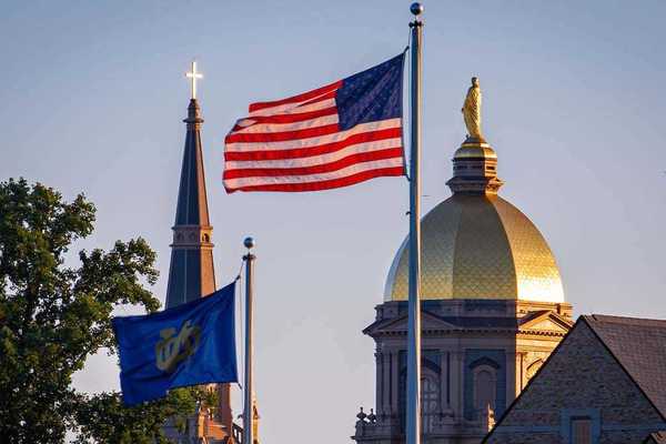 The Notre Dame and U.S. flags fly in front of the campus skyline.